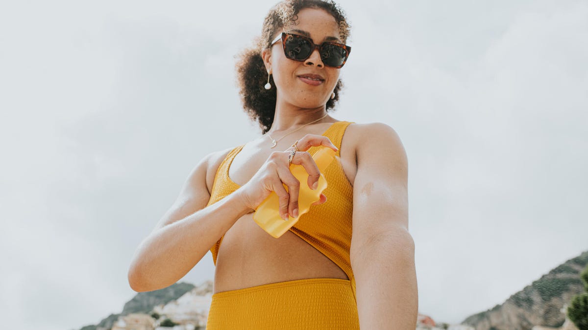 A person spraying themselves with sunscreen
