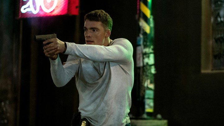 5 Great Netflix New Year's Show 2 Holding a gun in a scene of Peter Night Agent in a white sweater.