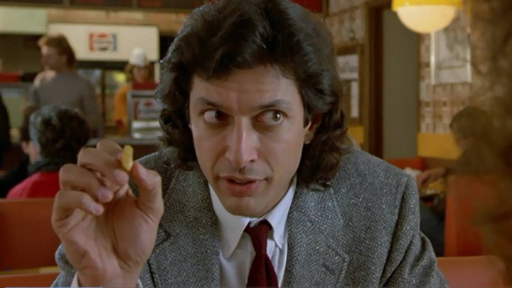10 Best Film Remake, Rank of All Time, Rank 4 Jeff Goldblum holding a piece of food in a dinner in a suit.